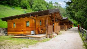 a wooden cabin with a porch and a fence at Camping Val di Sole in Peio