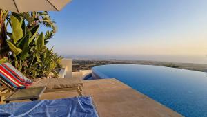 a view of a swimming pool with an umbrella and chairs at Breathtaking Panoramic Villa Sea View Infinity Pool in Tala