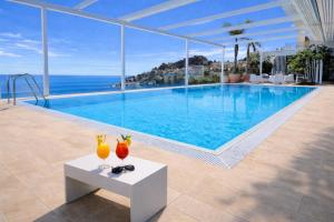 a swimming pool with two vases on a table in front of the ocean at MEDITERRANEAN SEASONS, VILLA MEDITERRANEA Taormina, Private Pool & Sea View in Taormina