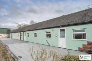 a row of green and white buildings at Birchenfield Holiday Cottages in Dilhorne