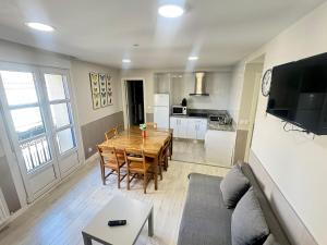 a living room with a wooden table and a kitchen at Apartamentos Logroño Centro in Logroño