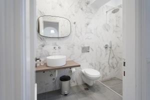 a white bathroom with a toilet and a mirror at Alexia Studios in Kolios +18 photos