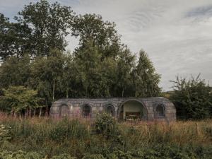 an old brick building in a field with trees at Boath Cabin in Auldearn