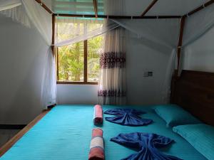a bedroom with a bed with blue sheets and a window at Villa Four Seasons in Mirissa