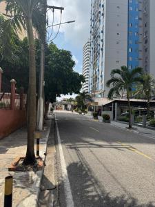 an empty street with palm trees and buildings at Apartamento no Umarizal in Belém
