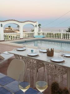a table with wine glasses next to a swimming pool at Villa Cala Lanuza in Alicante