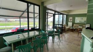 a restaurant with green chairs and tables and windows at Filoxenia Marias in Loutra Ipatis