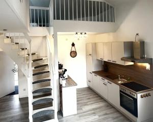 a kitchen with white cabinets and a spiral staircase at LT35a Haus Sternengucker in Dorum-Neufeld