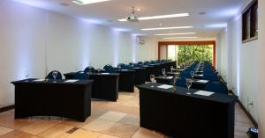a room with rows of tables and blue chairs at Hotel Pontal de Ubu in Anchieta +100 photos