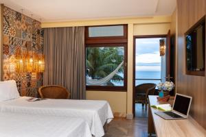 a hotel room with a bed and a desk with a laptop at Hotel Pontal de Ubu in Anchieta