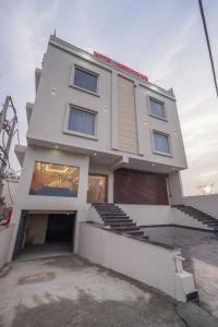 a white building with a parking lot in front of it at Hotel American inn in Nakodar