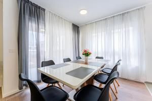 a dining room with a white table and black chairs at Flex SelfCheckIns 99 - 2 Bedrooms - Parking - Loggia in Velika Mlaka