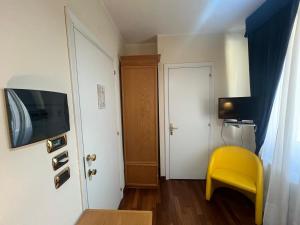 a small room with a yellow chair and a door at Hotel Liberty in Pattada