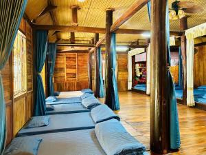 a row of beds in a room with wooden ceilings at Homestay Mường Lay in Bản Pong