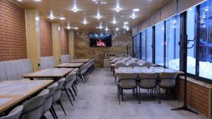 a dining room with tables and chairs and a tv at Old Well Hotel in Tsaghkadzor