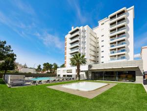 a large white building with a pool and a lawn at Alcazar Hotel & SPA in Monte Gordo