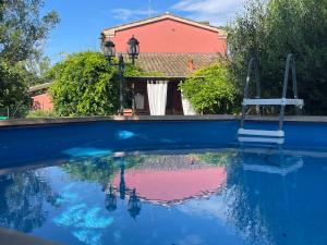 a blue swimming pool with a house in the background at Ca' Barbona in Lido di Classe