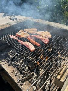 a group of sausages and meat cooking on a grill at Urban House - Ada in Ada