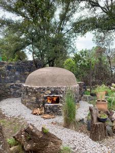 a stone oven with a fire in a garden at Cabaña Romántica, glamping Piedra Braza Orígenes in Ocoyoacac