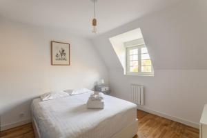 a white bedroom with a bed and a window at P'ty Solidor - 500m du port in Saint Malo