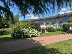 Ein Mann, der mit seinem Hund vor einem Gebäude spazieren geht in der Unterkunft Logis Hôtel Restaurant La Berteliere in Saint-Martin-du-Vivier