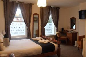 a bedroom with a bed and two large windows at Yarm View Guest House and Cottages in Yarm