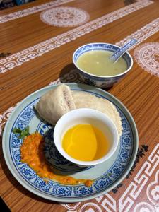 a plate of food with a cup of soup and a burrito at Valley View Homestay Lahaul in Gondla +38 photos