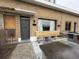 a brick building with a bench and a window at Schorrebloem in Lombardsijde