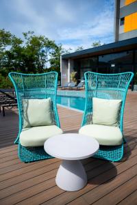 two chairs and a table on a deck with a pool at Liwe Hotels in Penha