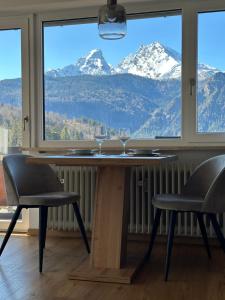a table with two wine glasses and a view of mountains at Ferienwohnung Bergidyll in Schönau am Königssee