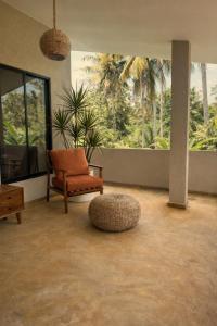 a living room with a chair and a ottoman at Drop Inn Studios in Ahangama
