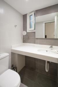 a white bathroom with a toilet and a sink at Villa ALEXIS in Koukounaries