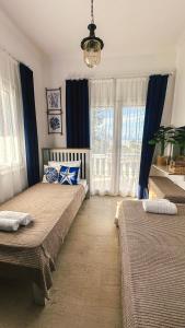 two beds in a room with blue curtains at Blue Pearl Molos in Mólos