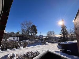 a snow covered street with a tree and the sun at Stylish 2-bedrooms apartment, smart TV, Netflix, parking - Oslo in Oslo