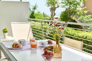 a table with a breakfast of bread and juice and flowers at JUST SUITES in Cervia