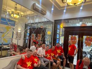 a group of men in red shirts sitting in front of a store at Memory Homestay Ông Chung in Lệ Thủy