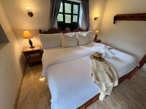 a bedroom with a large white bed with a hat on it at Hotel Beth Sarim in Villa de Leyva
