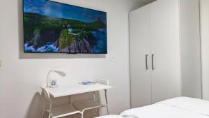 a white room with a bed and a tv on the wall at Rooms Koblar in Portorož