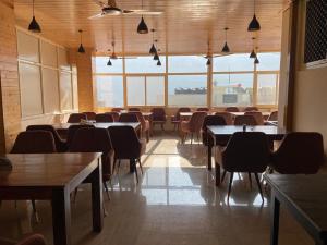 a dining room with tables and chairs and large windows at Hotel Blue Moon in Rishīkesh