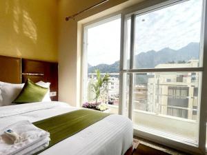 a bedroom with a bed and a large window at Hotel Blue Moon in Rishīkesh