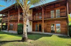 a wooden house with a palm tree in front of it at Casa Sol e mar Uruaú in Beberibe