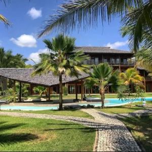 a house with a swimming pool and palm trees at Casa Sol e mar Uruaú in Beberibe