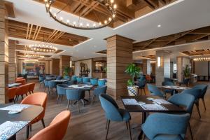 a dining room with tables and chairs and a chandelier at Ambassadori Goderdzi Hotel in Goderdzi