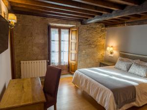 a bedroom with a bed and a wooden table at Hotel Vila As Pedras in Roxos