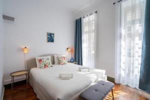 ein Schlafzimmer mit einem großen weißen Bett und Fenstern in der Unterkunft Zarco Suites by Sé Funchal in Funchal