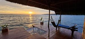 a deck with a hammock and the ocean at sunset at Yonas Homestay - Raja Ampat in Besir