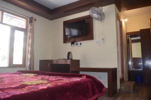 a bedroom with a bed and a tv on the wall at Hotel Tridev Manali in Manāli
