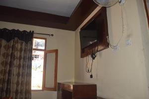 a kitchen with a television and a window at Hotel Tridev Manali in Manāli +18 photos