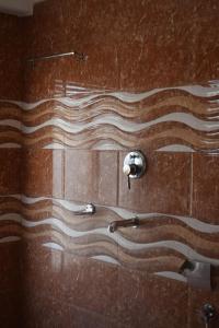 a bathroom with a shower with a wave design on the wall at Hotel Tridev Manali in Manāli