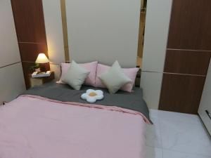 a teddy bear sitting on a bed with pink pillows at Mây homestay Phan Rang in Bắc Sớn